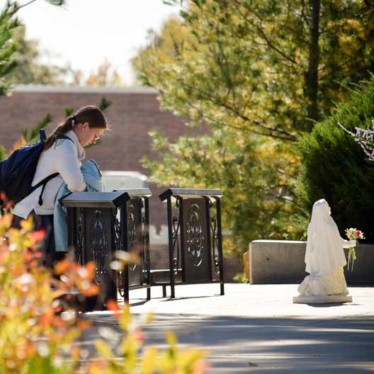 Student praying at Mary's Grotto